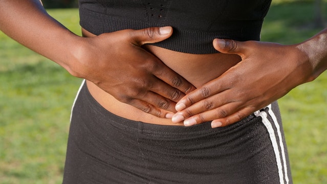 woman athlete holding her stomach - article discussing can you live with a hernia