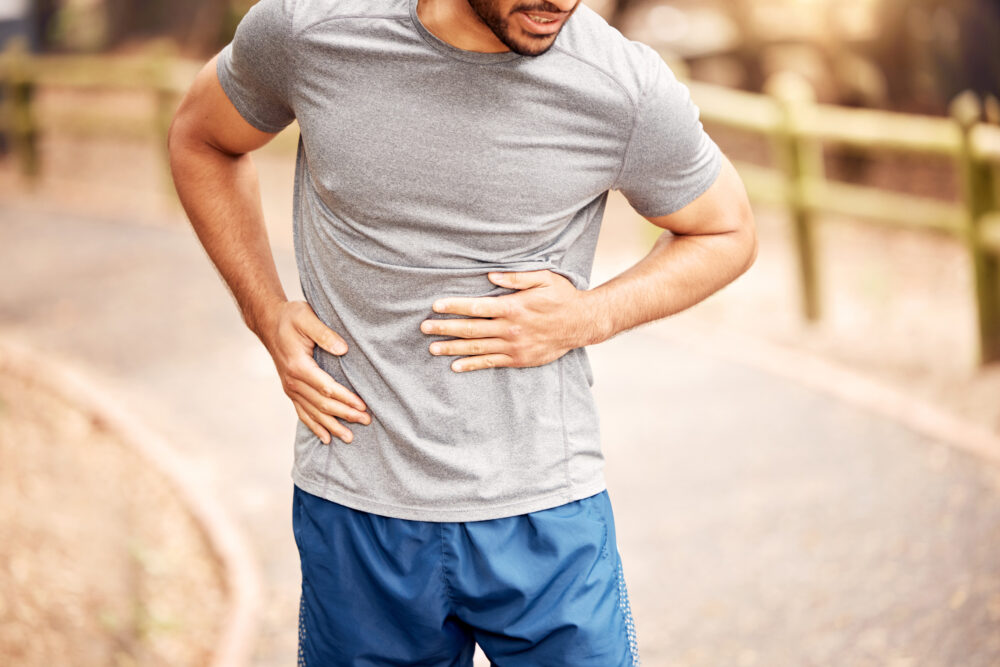man holding stomach while running outdoors in hernia pain
